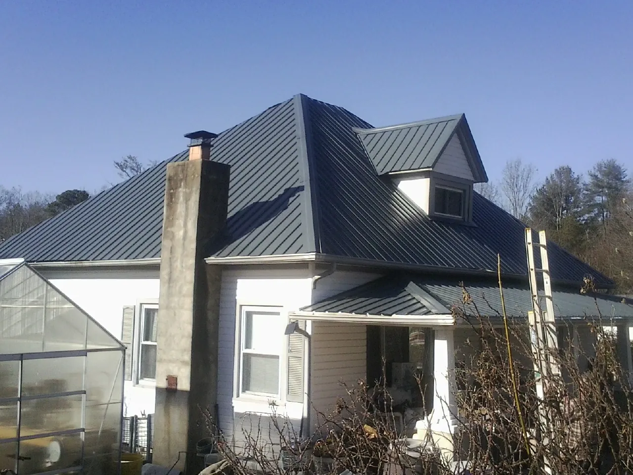 Dark blue standing seam metal roof on a white farmhouse with dormer — Slate & Tile Roof Repair by Roofing Brothers in Duncanville