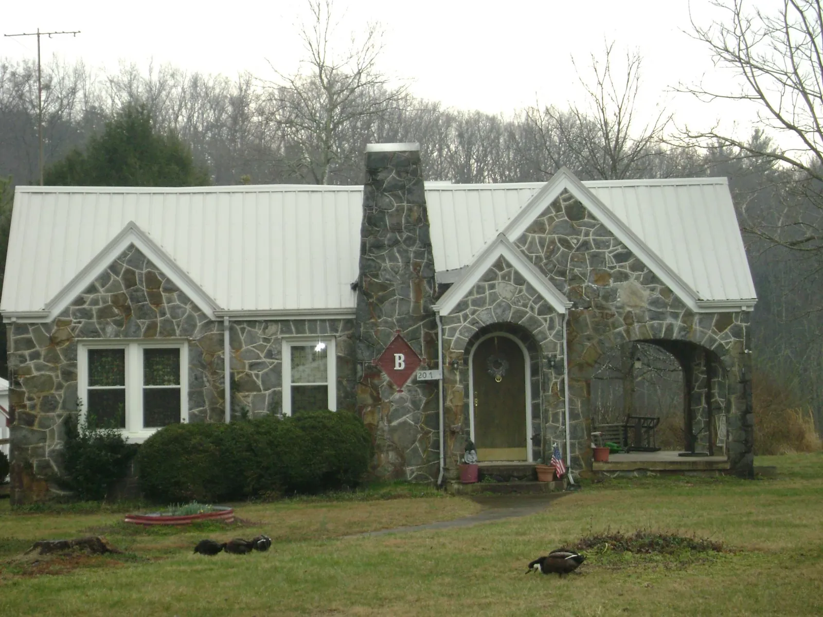 White metal roof on a stone cottage with steep gables in Duncanville