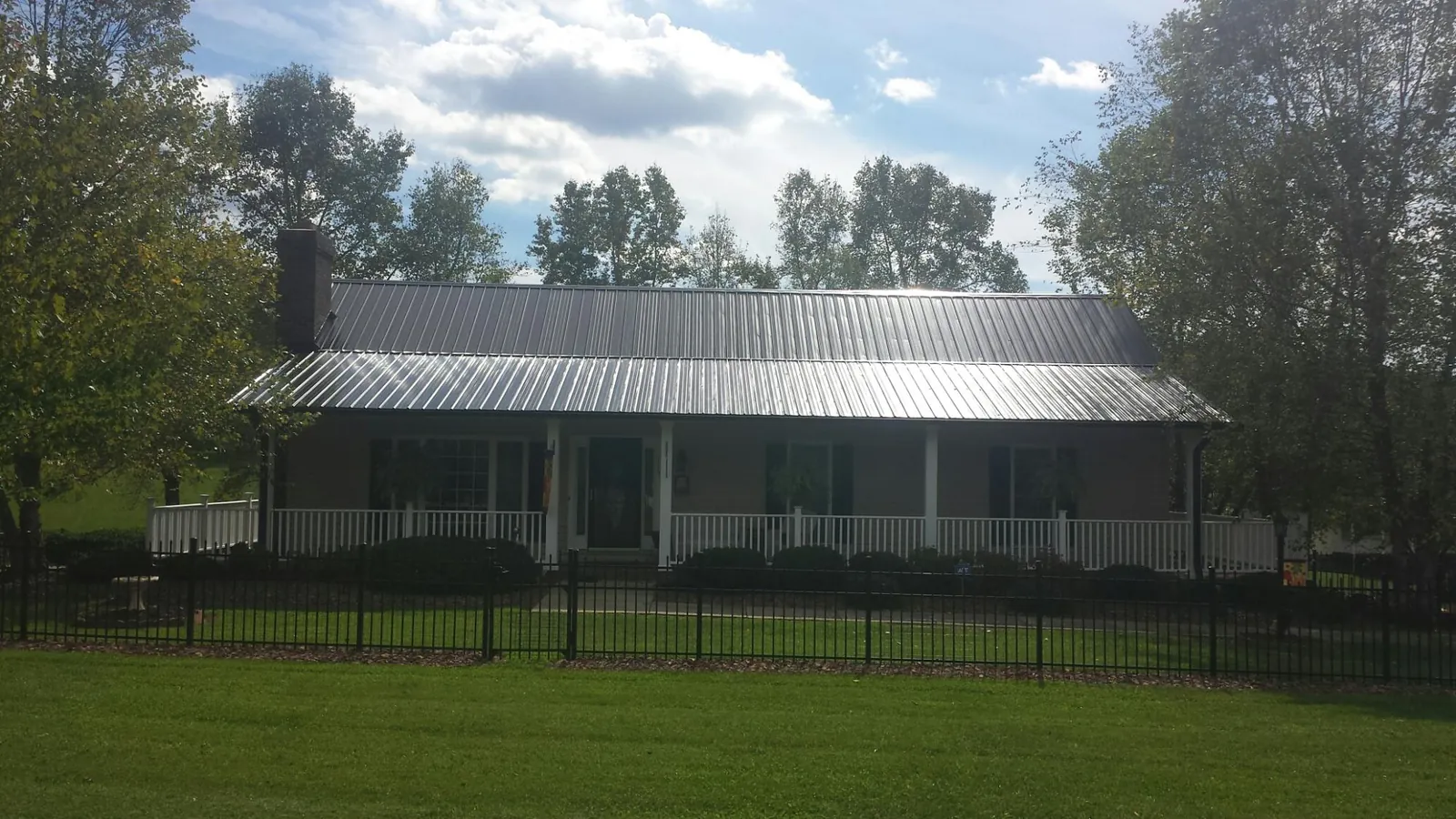 Gray metal roof on a brick ranch with a full width front porch — Gutter Guard Installation work by our crew in Duncanville