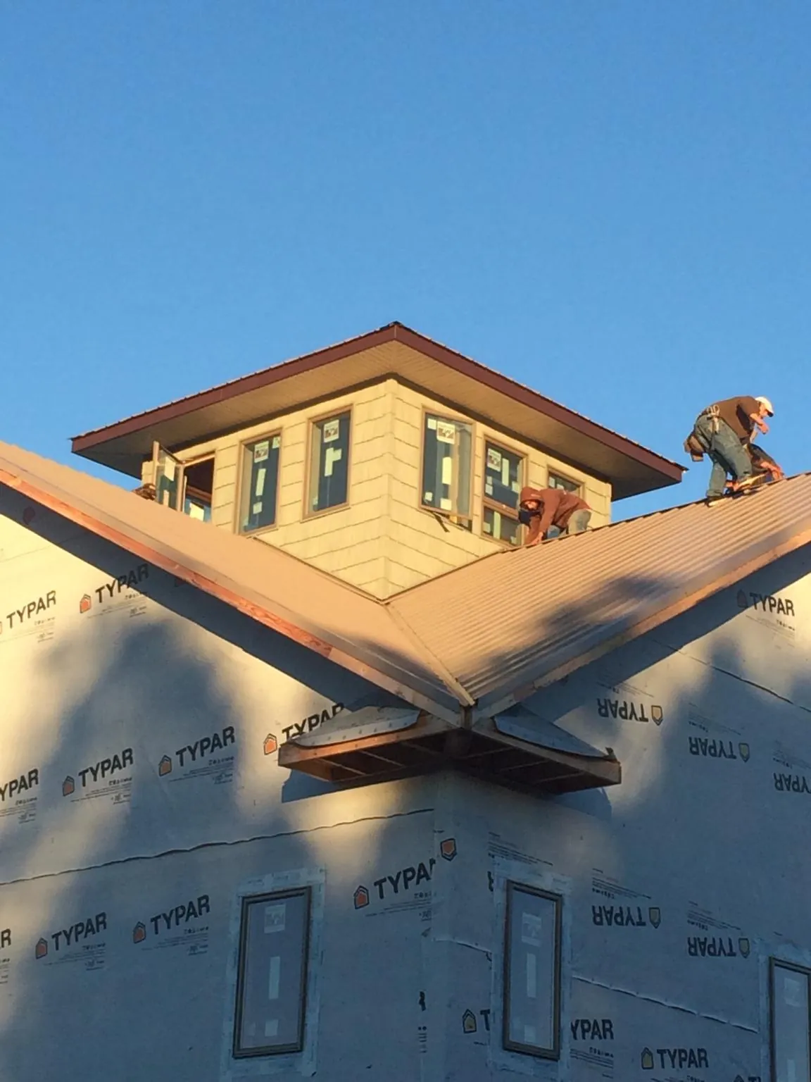 Roofers working around a rooftop cupola on a new metal roof at sunset — Roof Waterproofing in Duncanville by Roofing Brothers